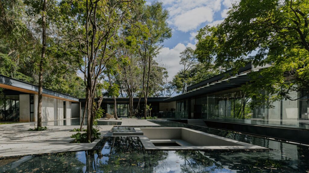 Central courtyard with reflective water features, concrete paved pathways, and preserved trees.