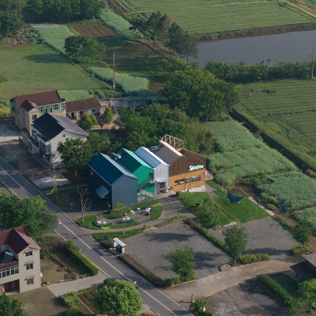 Aerial view of Spitfire Roastery by NOTA Architects nestled between green agricultural fields and village houses in Longfeng Village.
