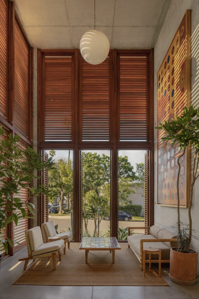 Double-height seating area in KAYA with floor-to-ceiling wooden louvered screens, warm lighting, and contemporary seating.