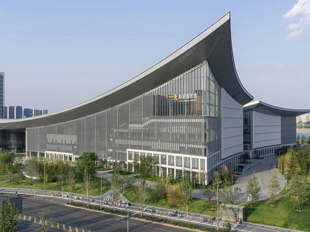 Low-angle exterior shot of the Xi'an Public Library facade displaying the dramatic upward curve of the roof corner and glass curtain wall.