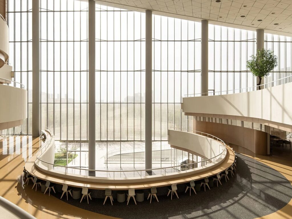 Interior view of a circular reading counter surrounded by floor-to-ceiling glass curtain walls and structural columns.