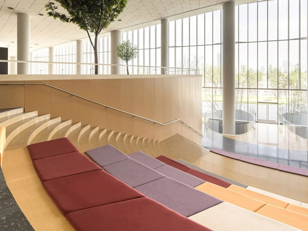 Stepped amphitheater seating with colorful cushions next to a grand atrium window in the Xi'an Public Library.