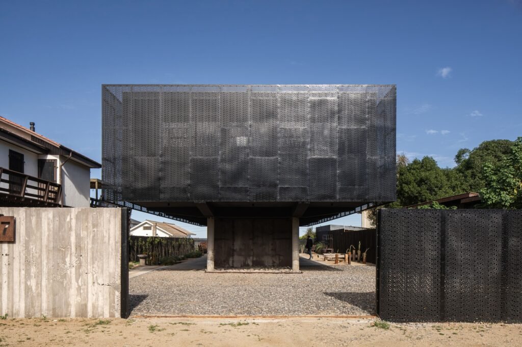Front view of Gandarillas House enclosed in a dark micro-perforated steel facade acting as a double skin envelope and security barrier.