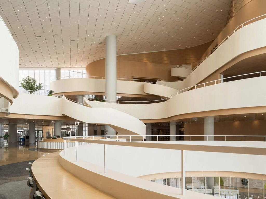 Multi-level interior atrium featuring fluid, sweeping white balconies and warm wood finishes inside the Xi'an Public Library.