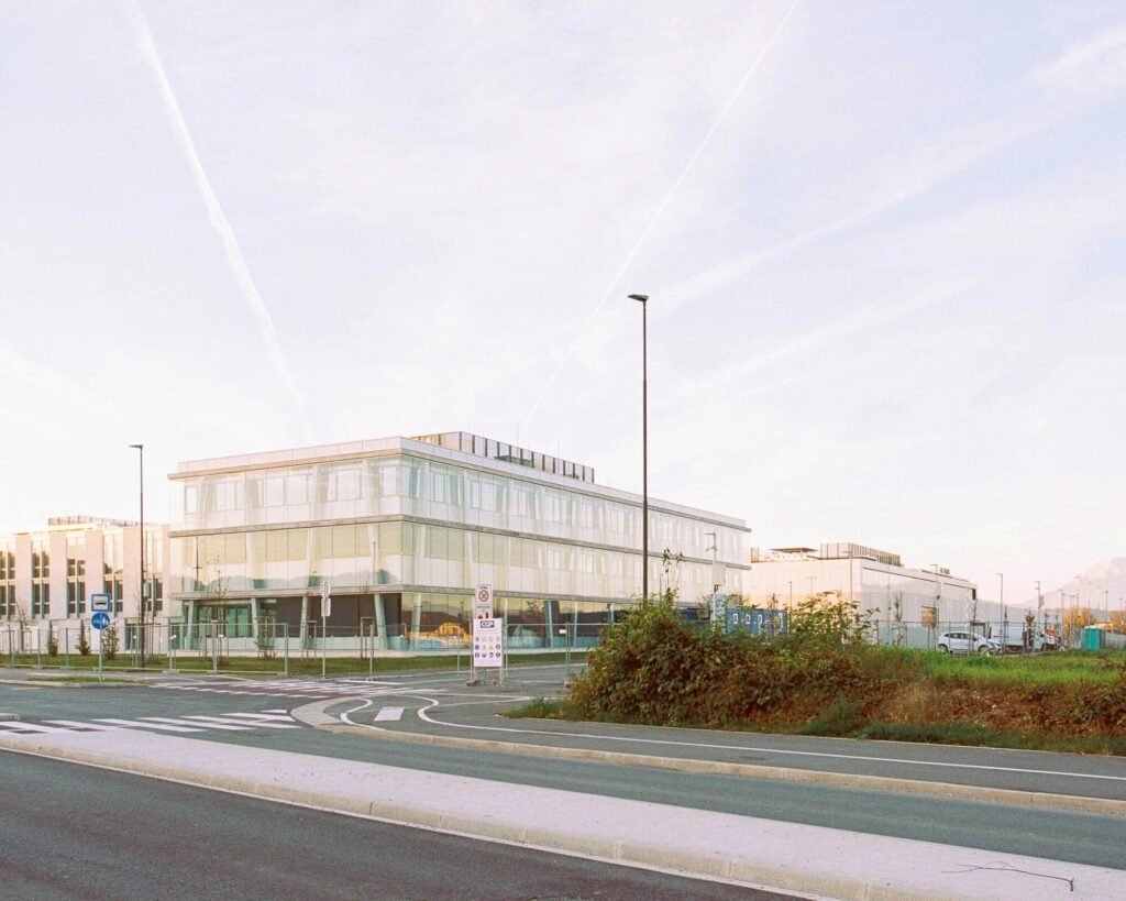 Exterior wide shot of the Educational Center building along Litijska Road in Ljubljana with the surrounding prison complex facilities behind it.
