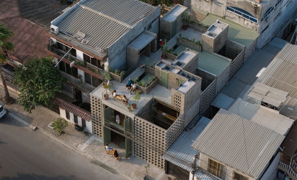 High-angle aerial drone view of the dense La Colmena housing project in Dur&aacute;n, highlighting the rooftop terraces with agricultural gardens, social gatherings, and multi-layered concrete-block volumes amidst a compact neighborhood.