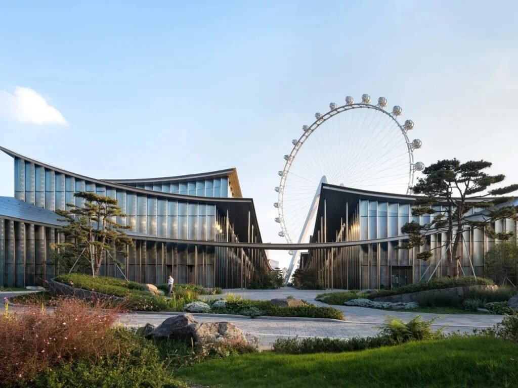 Street-level view looking through a central pathway framed by two glazed pavilions towards a distant Ferris wheel.