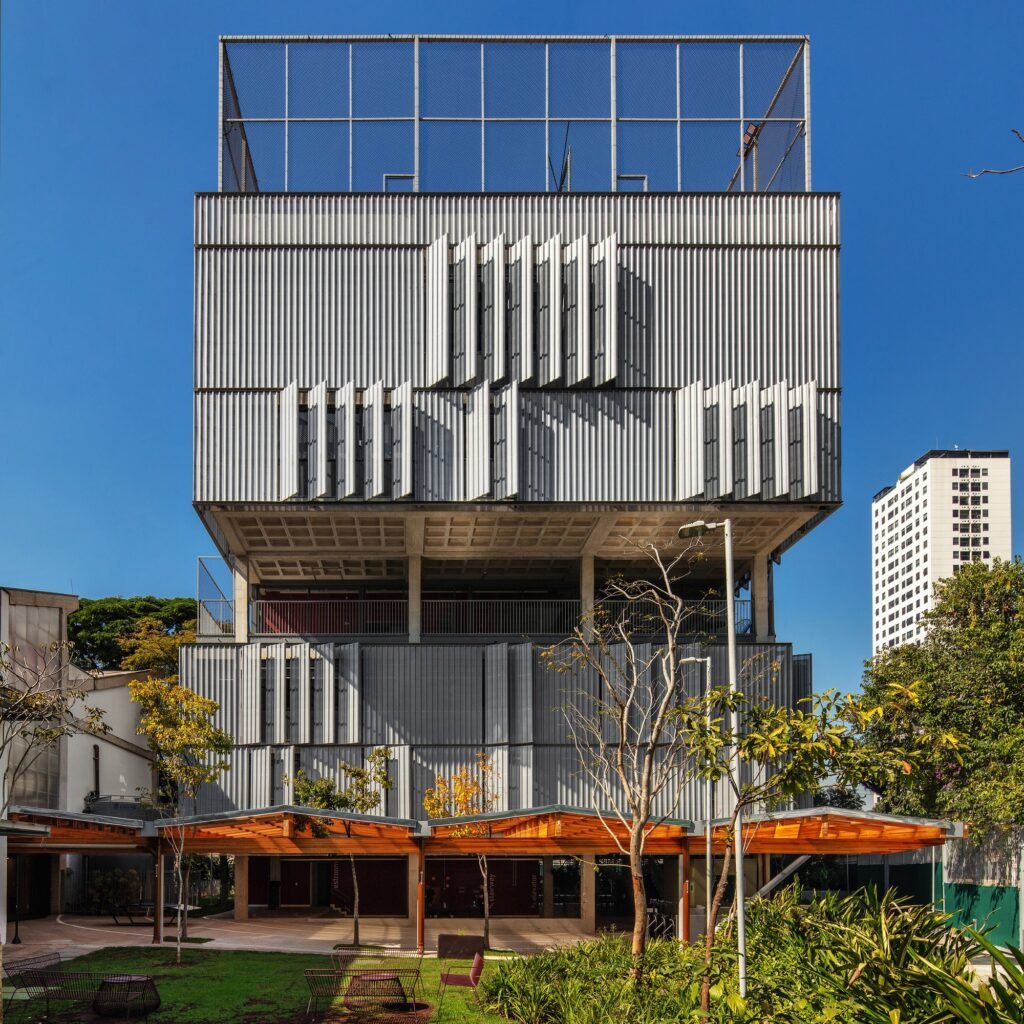 Contemporary High School building with perforated metal louvers, covered entrance canopy, and rooftop sports court.