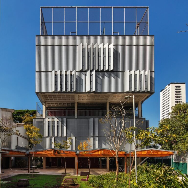 Contemporary High School building with perforated metal louvers, covered entrance canopy, and rooftop sports court.