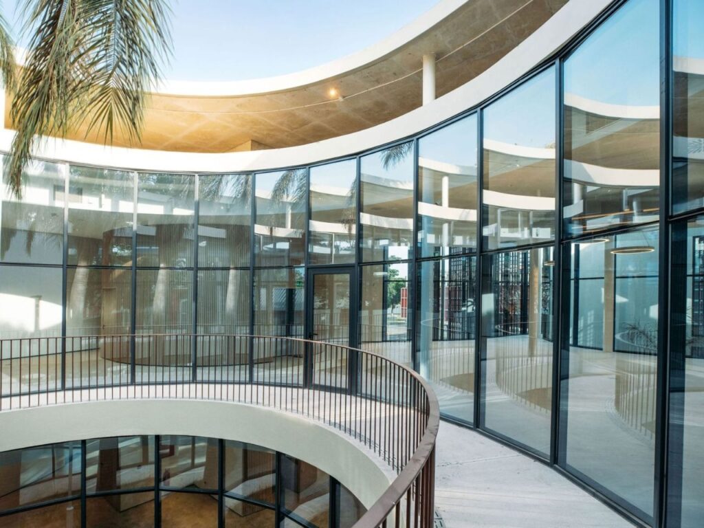 Upper-level curved balcony overlooking a glass-enclosed interior courtyard in Luanda Library.