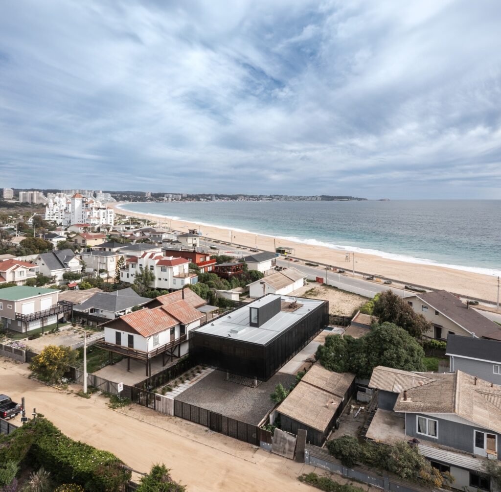 Aerial drone view of Gandarillas House near the coastline, highlighting its proximity to the beach and surrounding residential neighborhood.