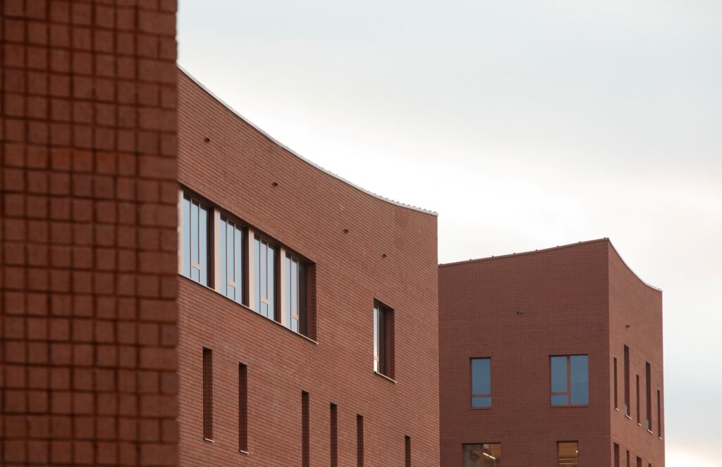 Close-up view of textured red brick facade and recessed windows of Campus Deleers buildings.