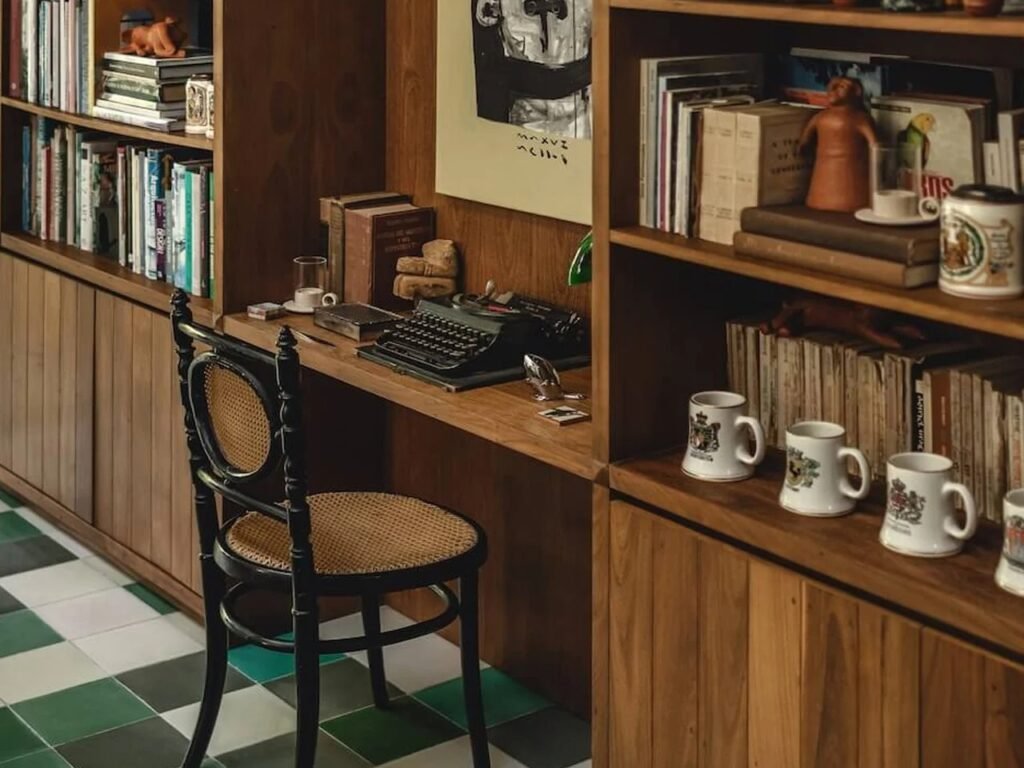 Custom tzalam wood bookcase and desk with vintage black cane chair, typewriter, and decorative items at Casa del Loro.