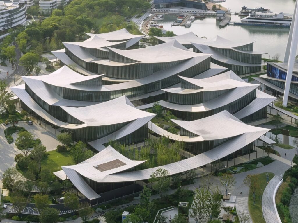 High-angle aerial view displaying the layered, rippling metal roofs over the museum pavilions set within lush landscaping.