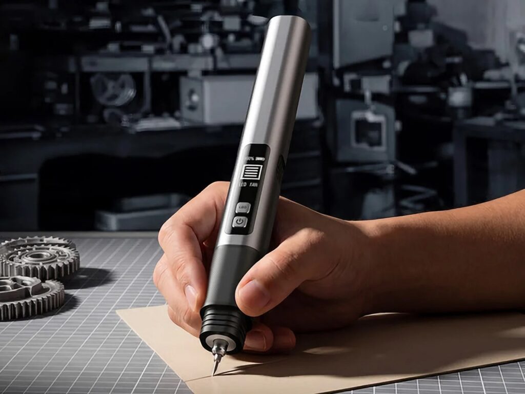 A hand holds the Sonic Cutter Max 10 in a precise pen grip, performing a delicate finishing operation on a fine edge of a material, with gears visible in the blurred workshop background.