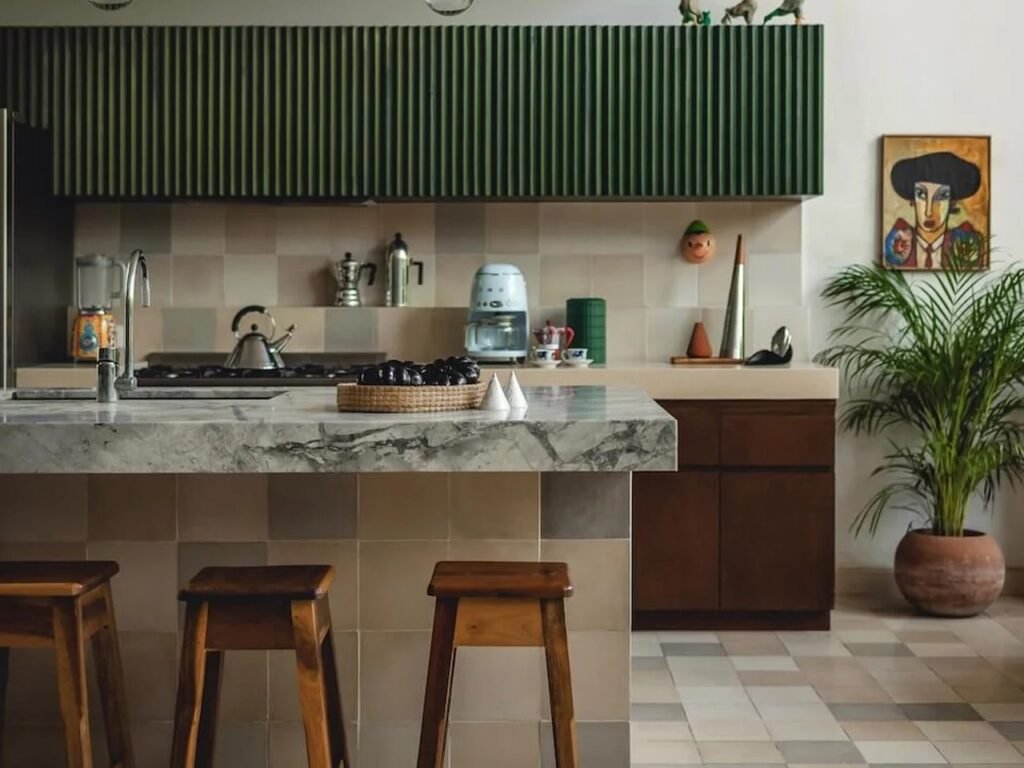 Contemporary kitchen with a marble-topped island, green fluted upper cabinetry, and checkerboard tiled floor at Casa del Loro.