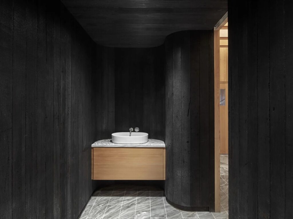 Charcoal black stained wood powder room with modern white vessel sink and stone countertop.