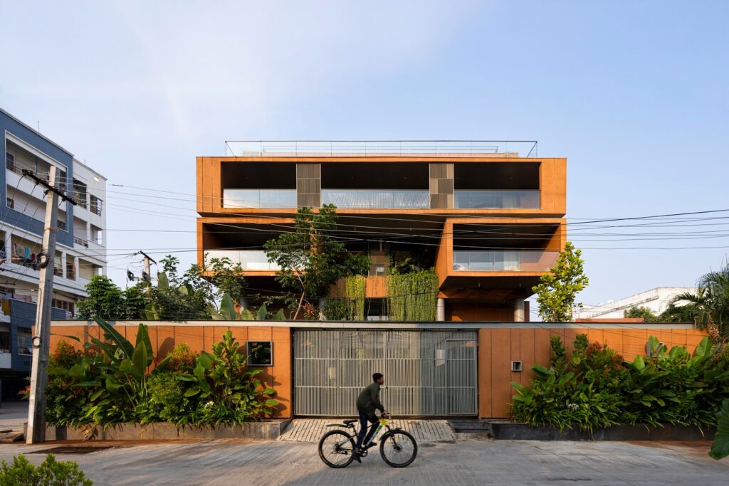 Front facade of Erra Kotta Residence featuring deep covered balconies, a gated boundary wall, and a cyclist passing on the street.