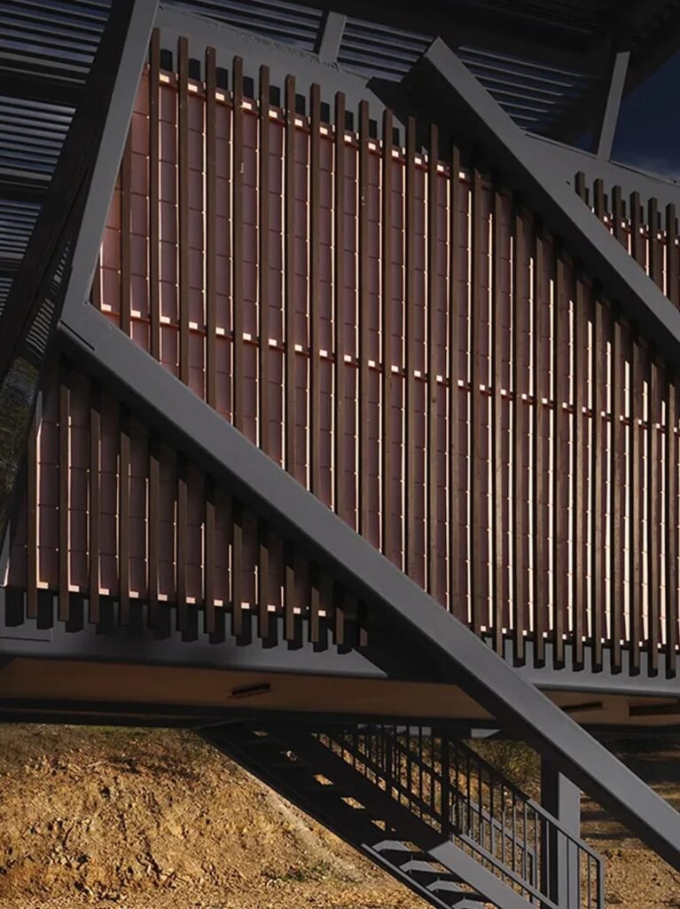 Close-up architectural detail of dark structural steel beams and vertical timber screen louvers on the exterior facade of Null House.
