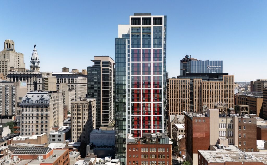 Mid-range elevation view of 210 South 12th residential tower rising amongst neighboring high-rise and mid-rise buildings in Philadelphia.