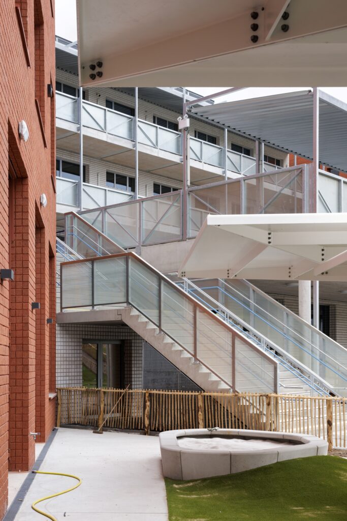 Exterior circulation staircase and steel walkways connecting upper educational levels at Campus Deleers.