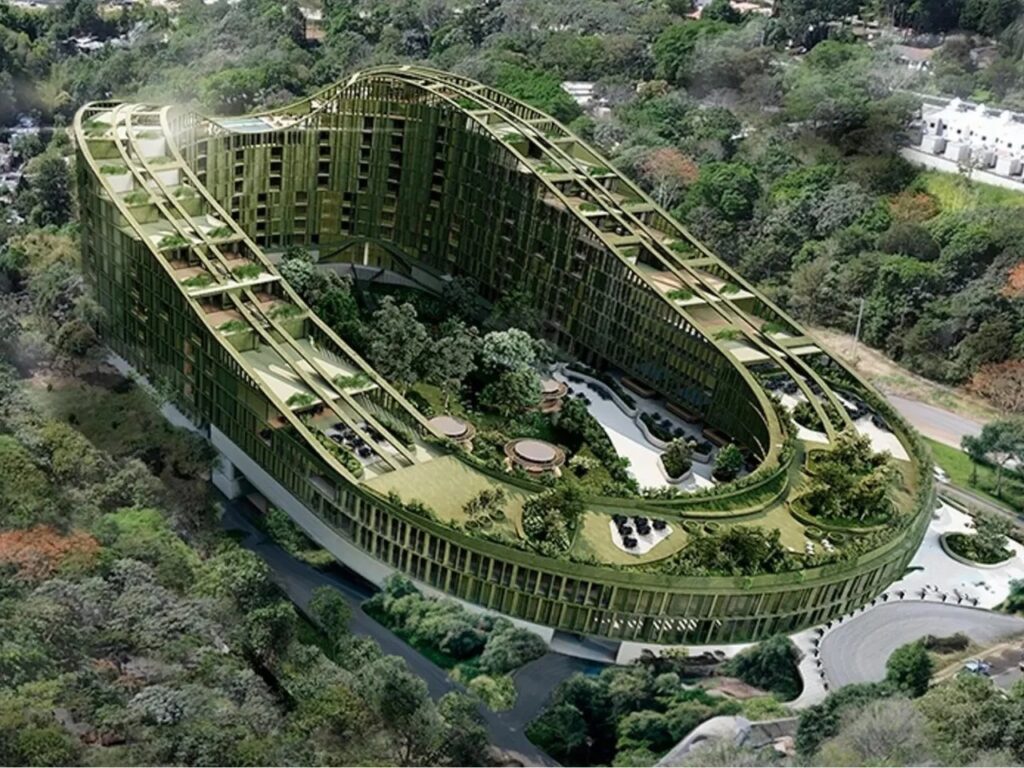 Perspective aerial view of the sweeping curved LTR1 housing complex surrounded by dense tropical forest.