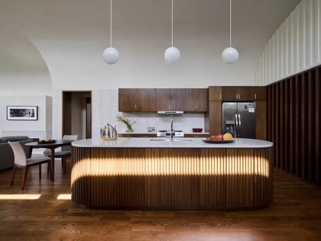 Contemporary kitchen with a slatted wood island, white countertop, pendant lights, and walnut cabinetry in Crescendo home.