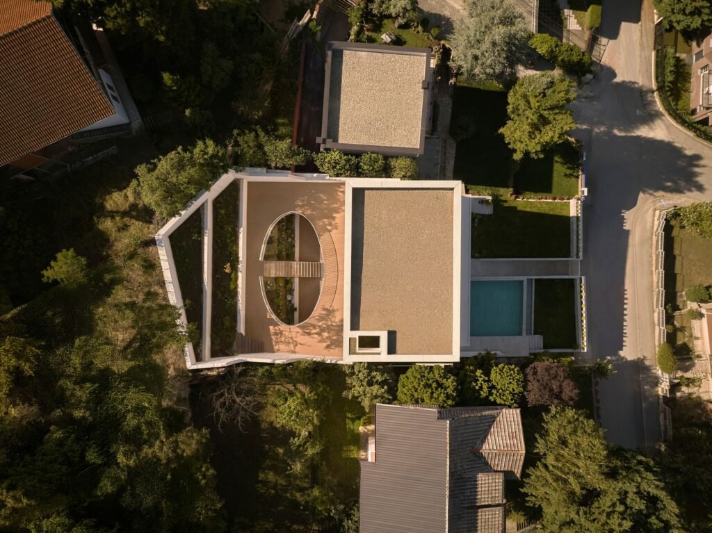 Top-down drone view of The Gallery residence showing the central courtyard opening, roof surfaces, pool, and layout.