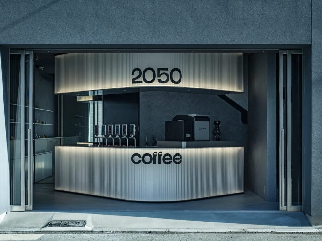 Illuminated angled counter and header with 2050 Coffee logo at the storefront entrance in Osaka.