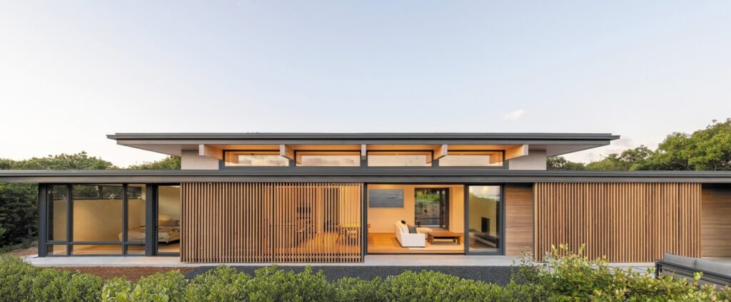 Front elevation of Veil House featuring vertical wooden slatted screens, floor-to-ceiling glass panels, and exposed roof beams.
