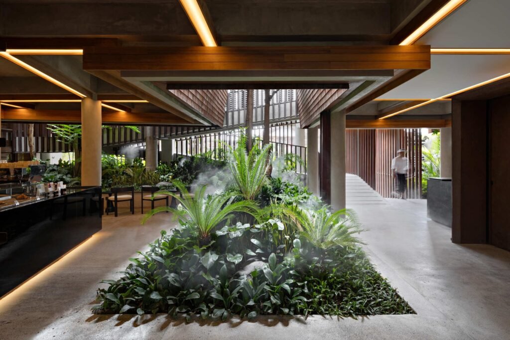 Central indoor garden bed with lush green ferns, tropical palm plants, ambient LED ceiling lighting, and mist cooling effect.