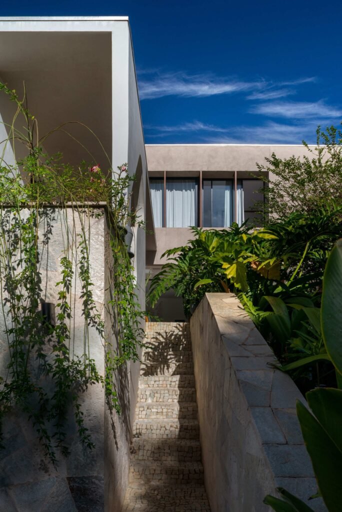 Stone-paved exterior staircase lined with tropical foliage and climbing plants leading up the terrain at Casa Noor.