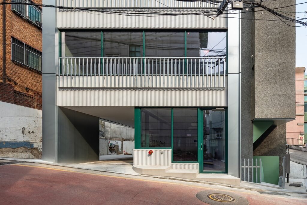Lower street-level facade of Bangbae building featuring corrugated metallic cladding and green window frames.