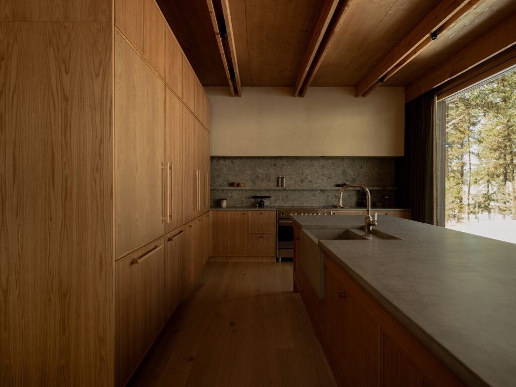 Full view of custom wooden kitchen cabinets and island counter under exposed CLT wood ceilings.