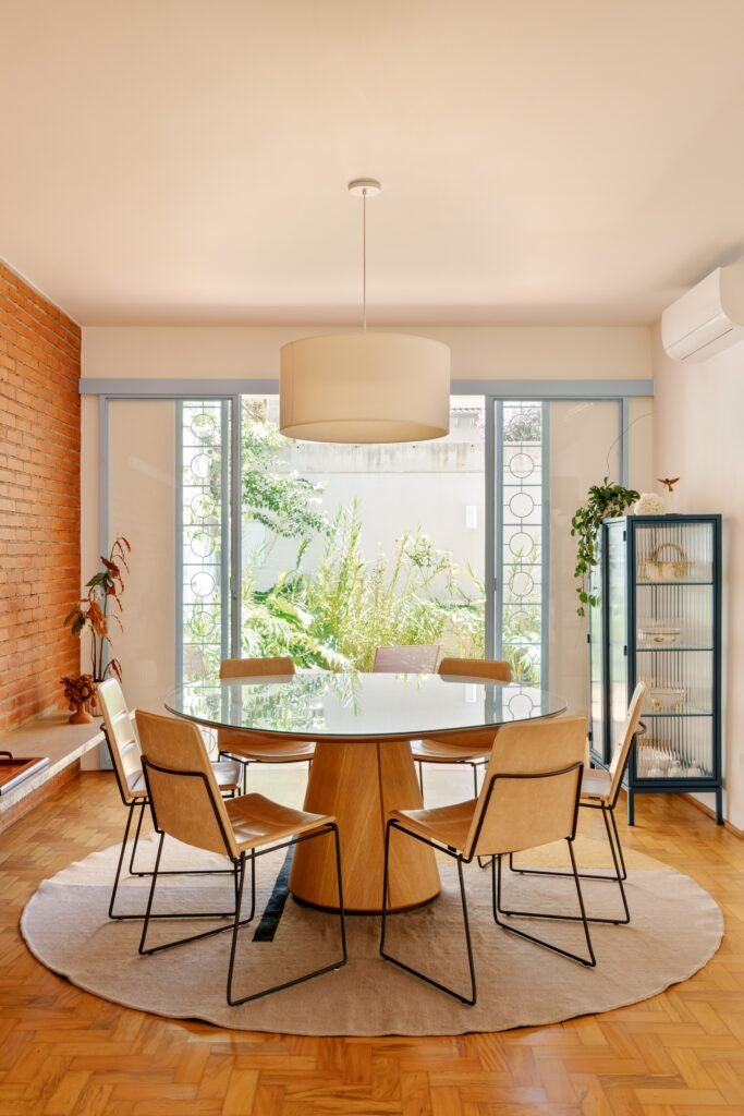 Dining table centered in front of large glass sliding doors looking out toward the lush green garden in Casa M.