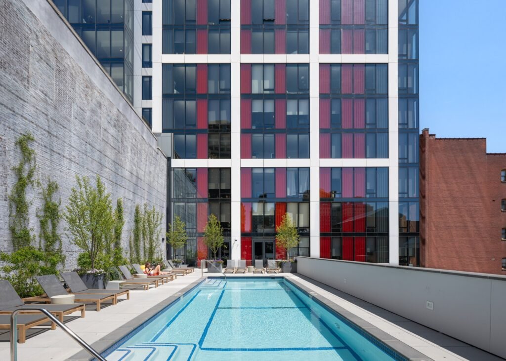 Outdoor swimming pool deck at 210 South 12th surrounded by lounge chairs and the tower's red and white facade.