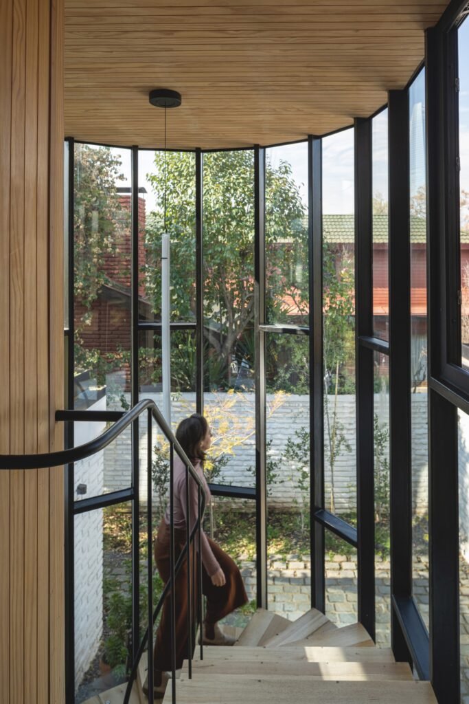 Spiral staircase surrounded by a curved glass enclosure connecting the upper and lower floor levels.