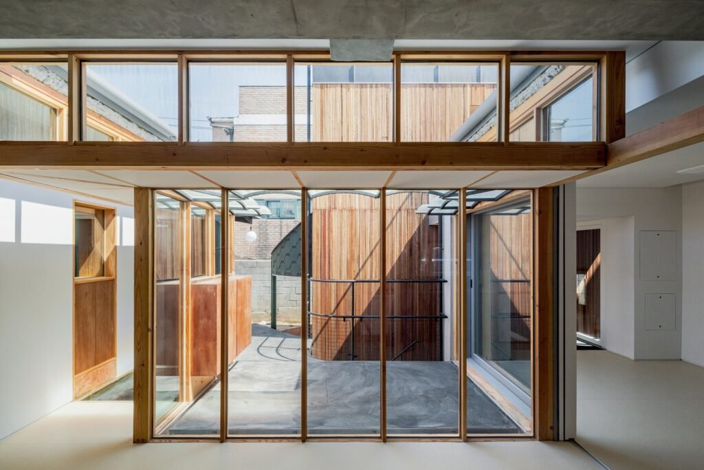 Bright interior living space with wooden window mullions looking out toward the central courtyard, sunken passageway, and south annex.