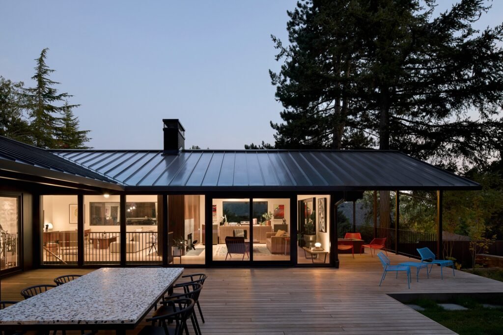 Exterior wooden deck and patio of the main house at evening with interior lights reflecting through large sliding glass doors.