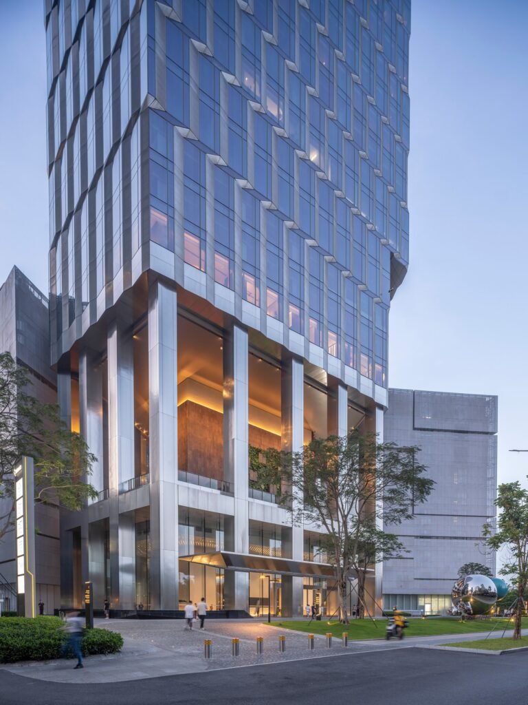 Ground-level entrance lobby of Kingdee HQ Tower with tall columns and open urban living room concept illuminated at dusk.
