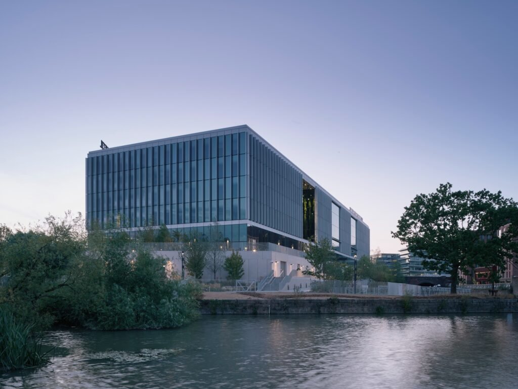 Exterior dusk view of Temple Quarter Enterprise Campus with glowing interior lights reflected on the water surface.
