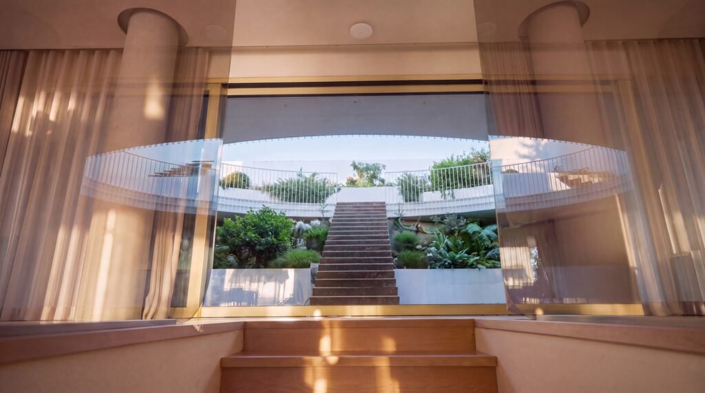 View from interior living space looking out through floor-to-ceiling glass to the central courtyard staircase and garden.