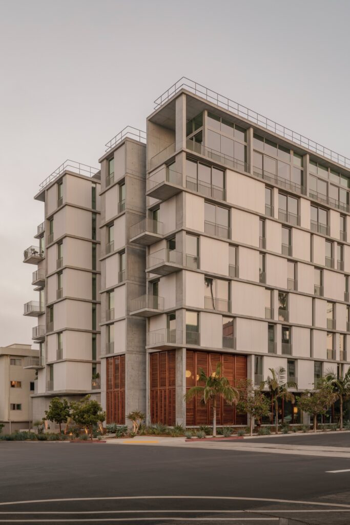 Corner view of KAYA building in San Diego showing the articulated facade, corner balconies, and street-level wooden shutters.