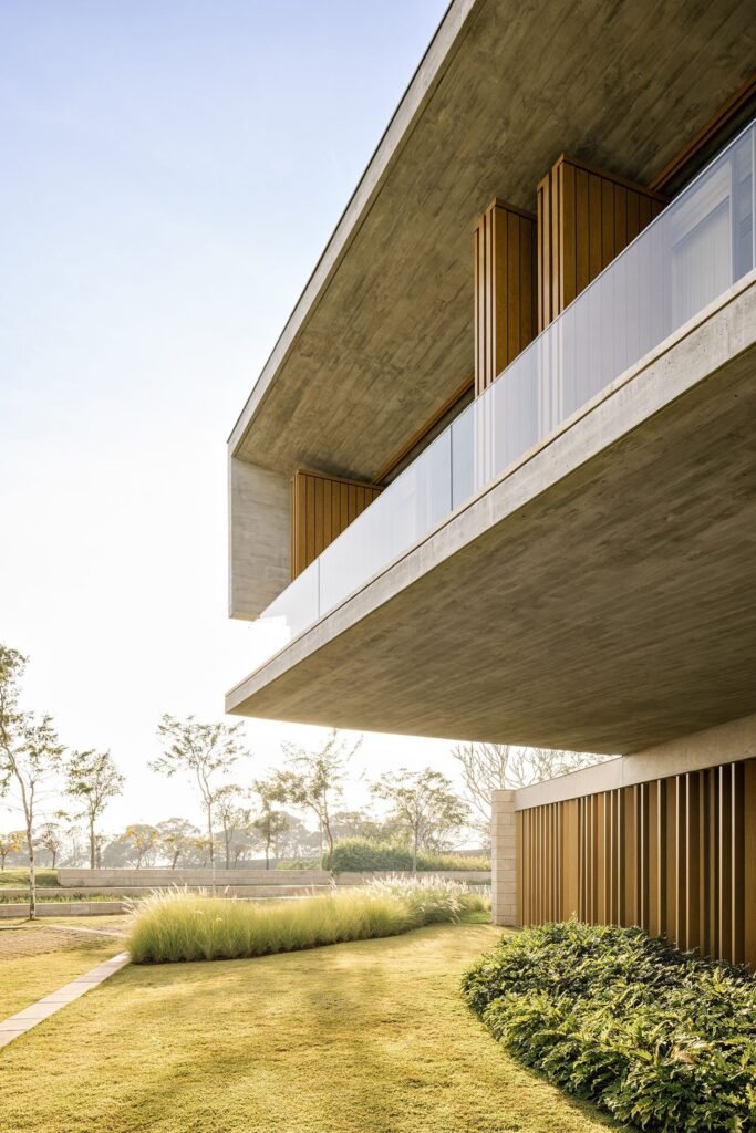 Close-up view of a massive exposed concrete cantilever slab with glass balustrade over green lawn.