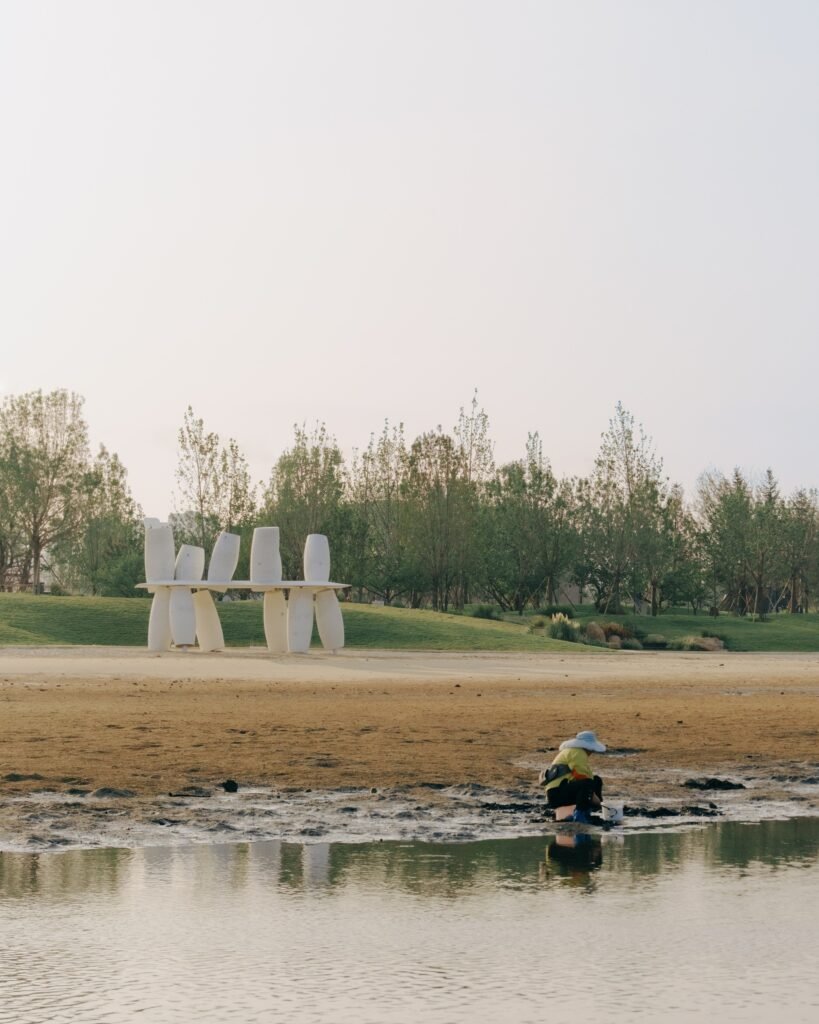Wide shot of the Coral pavilion situated along the beach with a local resident working on the low-tide mudflats in the foreground.