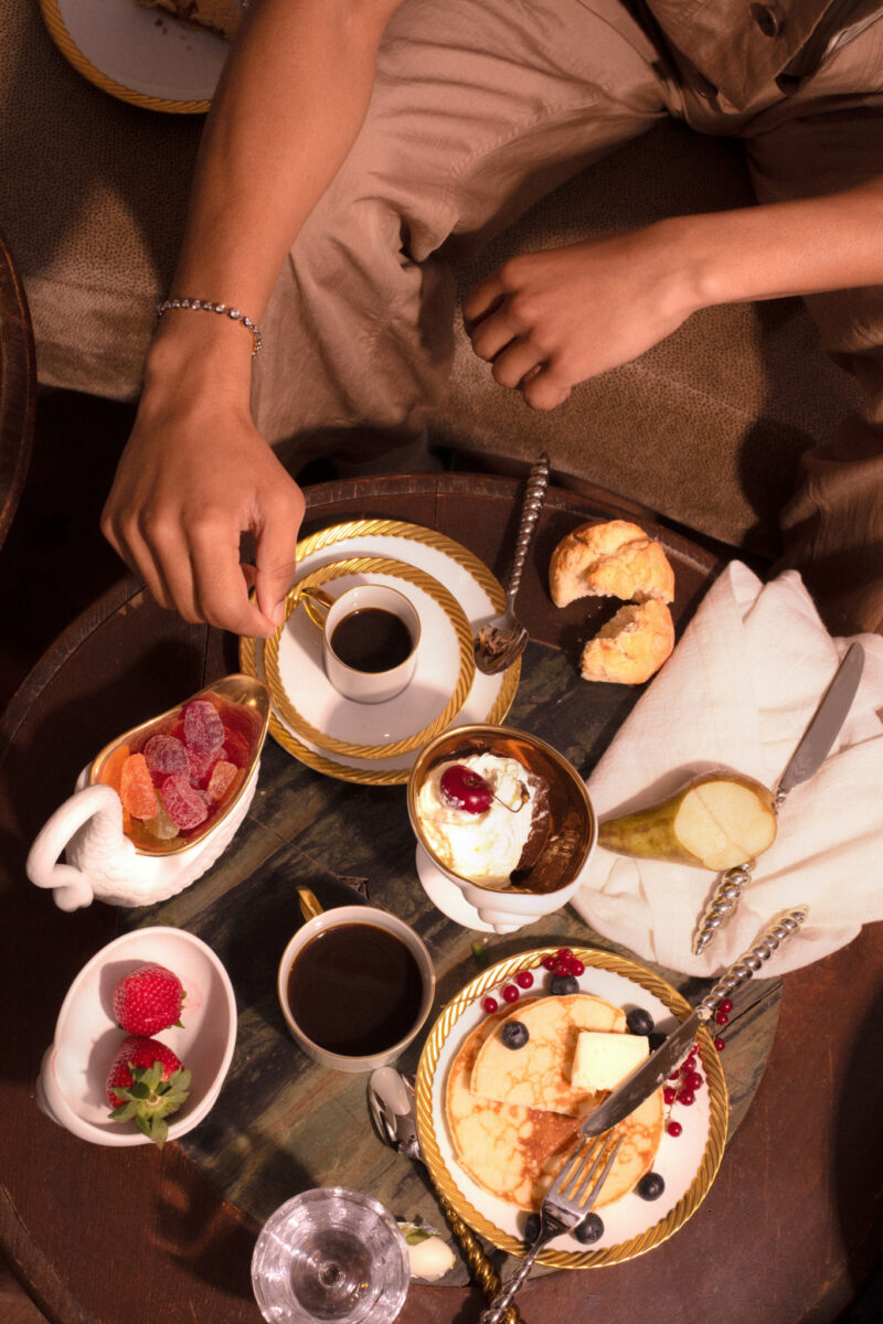 A breakfast table with coffee, fruit, pastries, and table objects from the L’OBJET x Jessica McCormack collection.