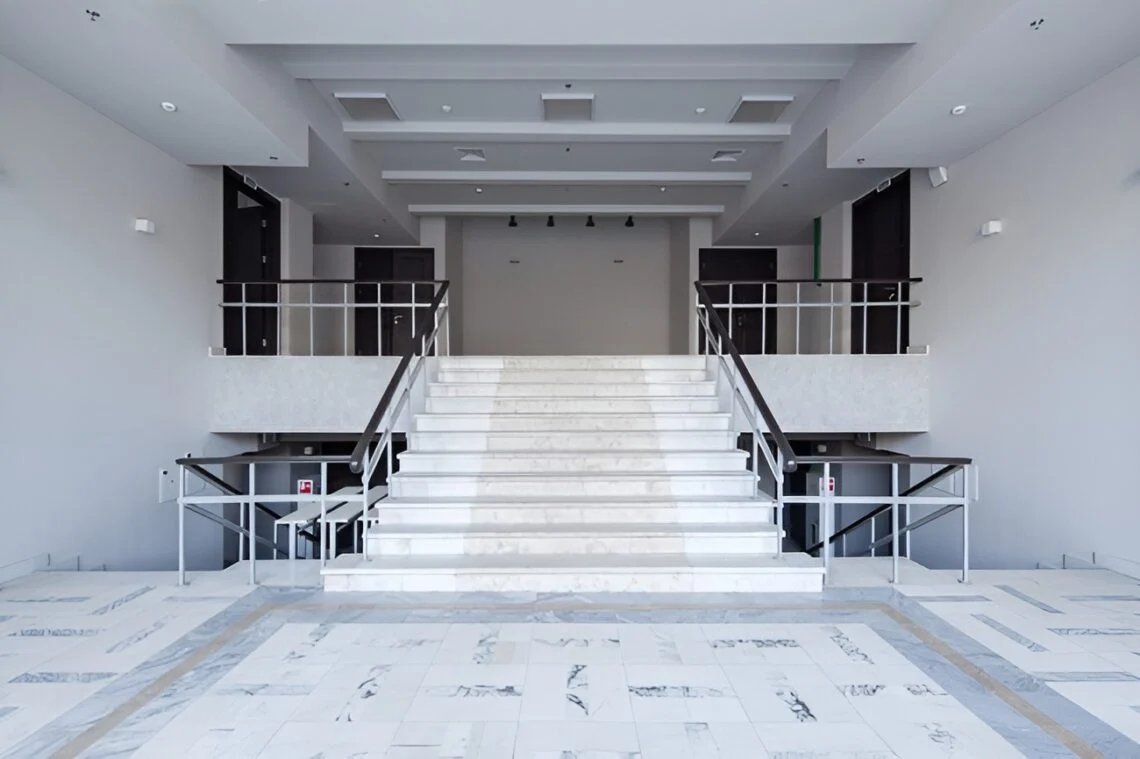 Auditorium interior showing tiered seating, stage space and large windows
