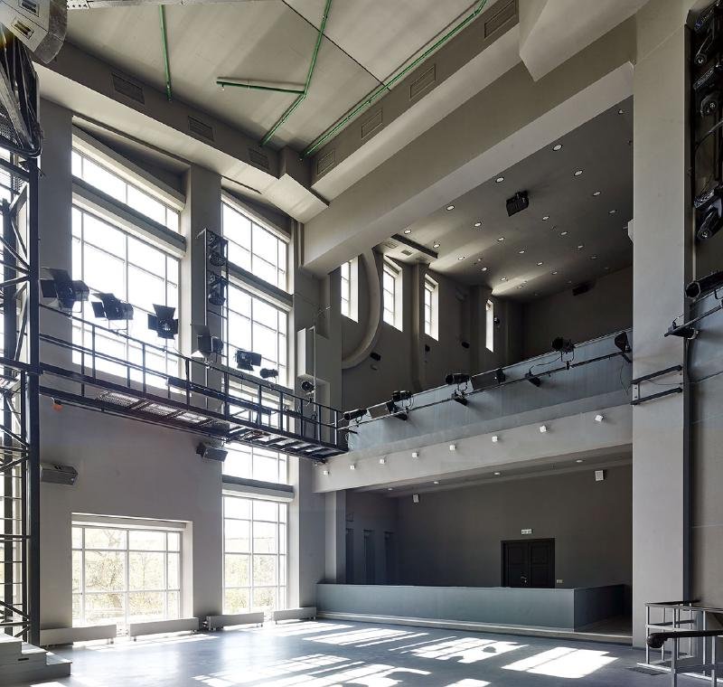 Auditorium interior showing tiered seating, stage space and large windows