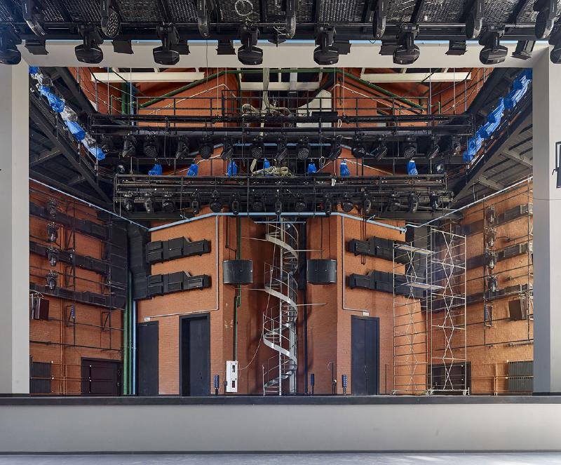 Auditorium interior showing tiered seating, stage space and large windows