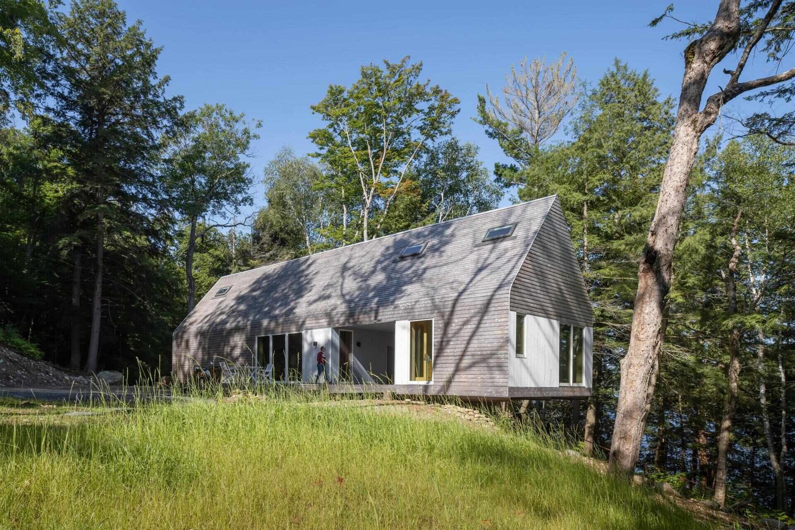 A modern prefab cottage in Magnetawan, Canada, designed with a simple gabled form, cedar siding, and an elevated structure that blends into the surrounding forest landscape.